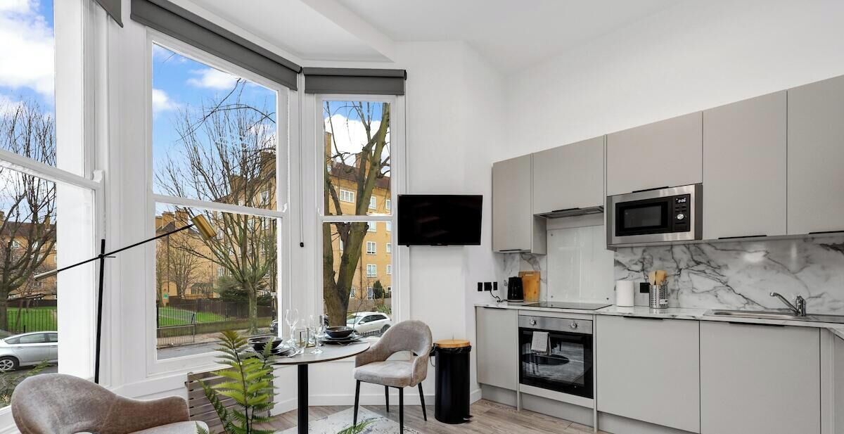A modern kitchen with a large window, a flat-screen TV, and a built-in oven.