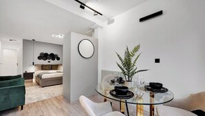 Un interior moderno con una mesa de comedor de vidrio, una cama y un sillón verde.