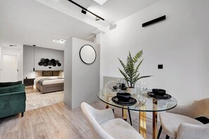 A modern interior with a glass dining table, a bed, and a green armchair. - Sleek & Stylish Studio in London (London)