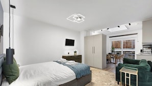 Un dormitorio moderno con cama, mesita de noche y vistas al salón.