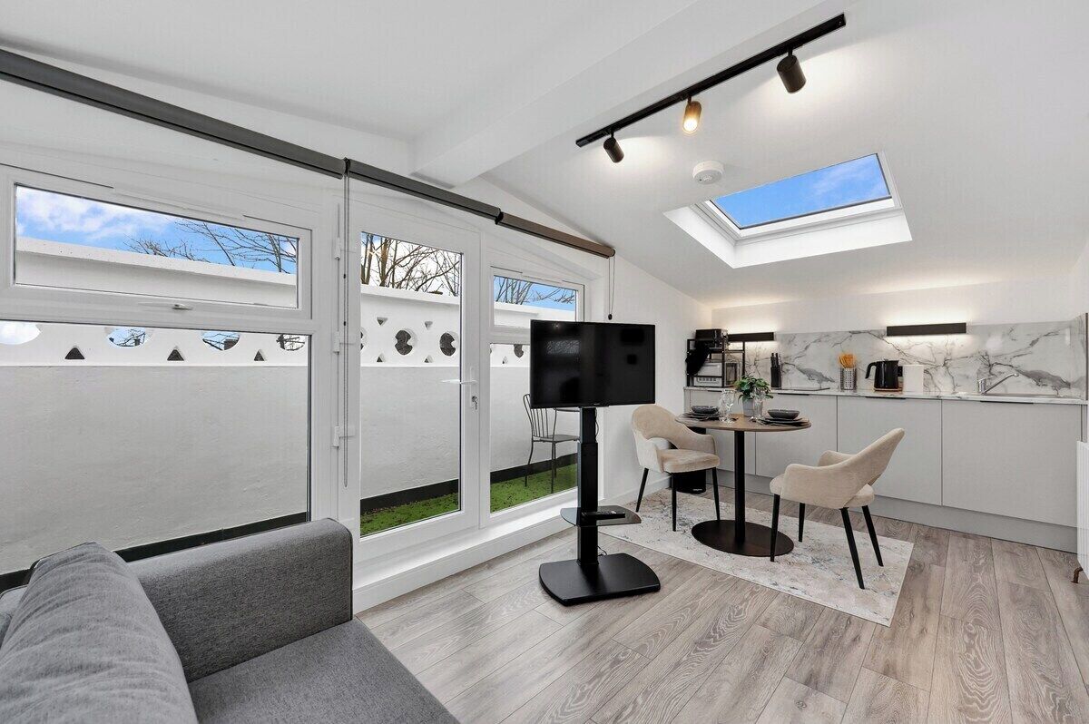 Ein modernes Wohnzimmer mit Flachbildfernseher, Essbereich und einer Küche mit Marmorarbeitsplatten.