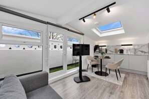 A modern living space with a flat-screen TV, a dining area, and a kitchen with marble countertops. - Large Studio Flat in London - With Terrace! (London)