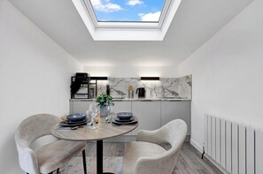 A modern kitchen with a skylight, marble backsplash, and a dining area with a round table and chairs. - Large Studio Flat in London - With Terrace! (London)