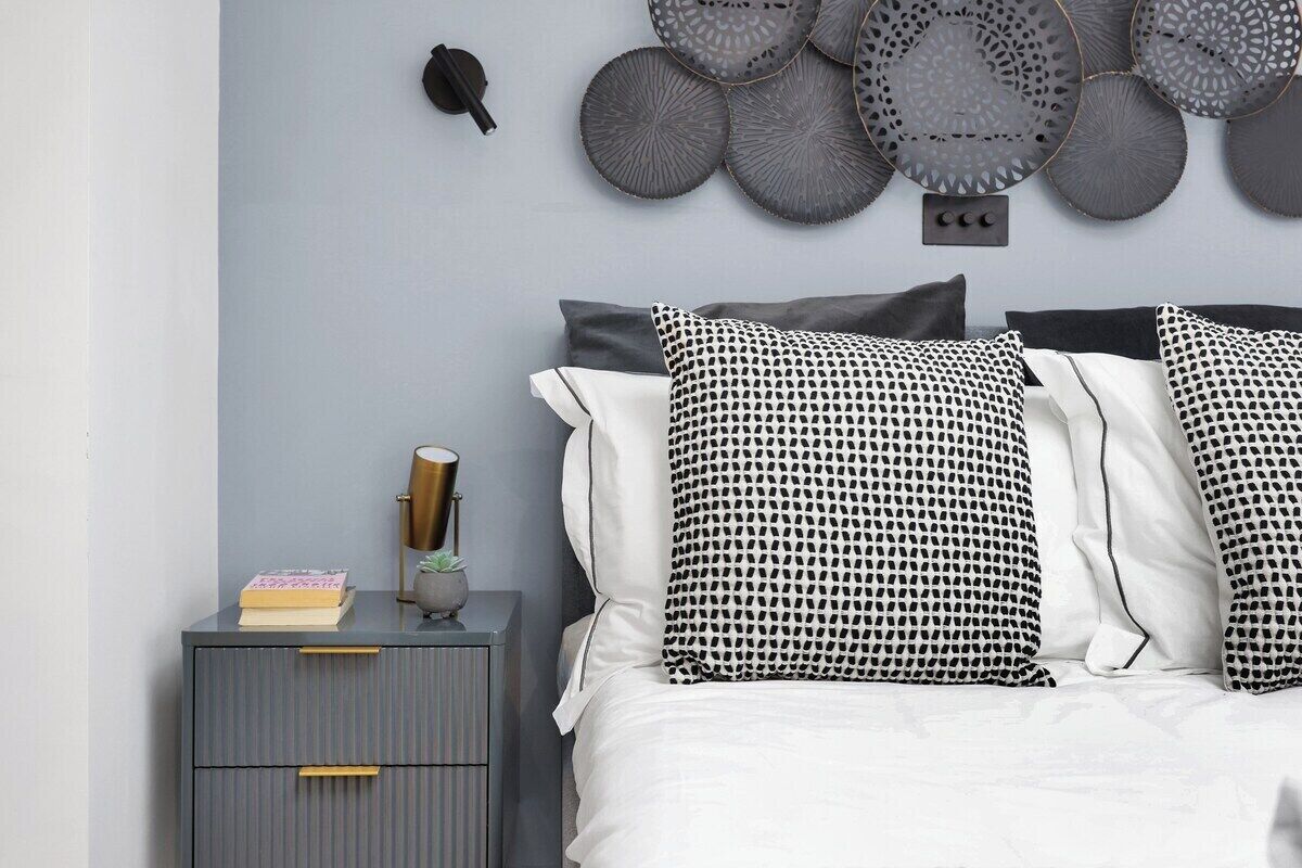 Une chambre à coucher avec un lit, une table de chevet et des œuvres d’art décoratives au mur.