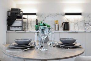 A round dining table with a modern design, equipped with plates, bowls, and wine glasses. - Large Studio Flat in London - With Terrace! (London)