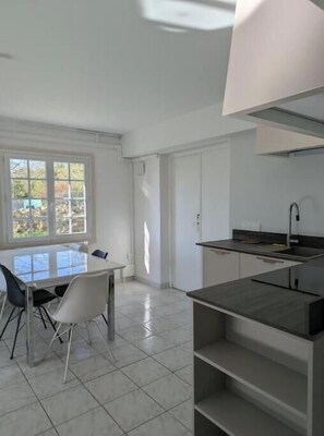 A modern kitchen with a dining area, large windows, and a view of the outdoors. - Bright T2 in the heart of the vineyards - 25 min from Bordeaux (Prignac-et-Marcamps)