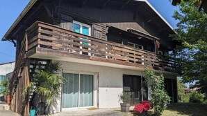 A two-story house with a balcony, a sliding glass door, and a small garden. - Bright 2-Bedroom Apartment in the Heart of the Vineyards – 25 Minutes from Bordeaux (Prignac-et-Marcamps)