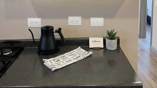 Een keuken met een koffiezetapparaat, een deurmat en een potplant.