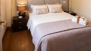 Een keurig opgemaakt slaapkamer met een bed, nachtkastjes en een bedtafel.