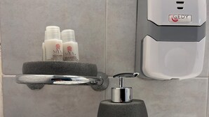 Ett badrum med en modern handfat, en tvålpump och en hylla med toalettartiklar.