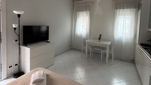 Ett modernt hotellrum med en säng, en TV, ett skrivbord och ett matbord.