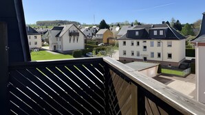 A residential area with houses, a clear sky, and a balcony with a railing. - Maisonette Apartment with Balcony, Shared Garden, Wi-Fi, Playground, Large Garden (Oelsnitz/Erzgebirge)