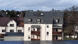 A multi-story building with balconies, a covered parking area, and a flat roof. - Maisonette Apartment with Balcony, Shared Garden, Wi-Fi, Playground, Large Garden (Oelsnitz/Erzgebirge)