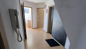 A hallway with a wooden floor, a telephone, and a door leading to another room. - Maisonette Apartment with Balcony, Shared Garden, Wi-Fi, Playground, Large Garden (Oelsnitz/Erzgebirge)