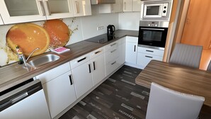 A modern kitchen with white cabinets, a built-in microwave, an oven, and a coffee machine. - Maisonette Apartment with Balcony, Shared Garden, Wi-Fi, Playground, Large Garden (Oelsnitz/Erzgebirge)