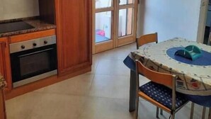 Una cocina con armarios de madera, una estufa y una mesa de comedor con sillas.