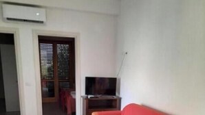 Una sala de estar con sofá, televisión, mesa y sillas.