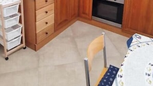 Una cocina compacta con armarios de madera, un lavamanos de acero inoxidable y un horno empotrado.