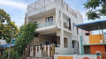 A multi-story residential building with a balcony, air conditioning units, and a gated entrance.