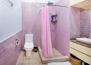 Ein Badezimmer mit Toilette, einer Dusche mit rosa Vorhang und einem Waschbecken.