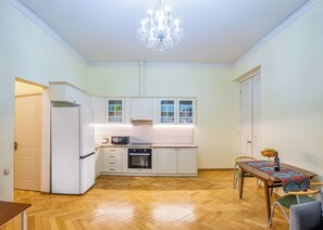 Eine kompakte Küche mit weißen Schränken, einer Mikrowelle, einem Backofen und einem Essbereich mit Tisch und Stühlen.