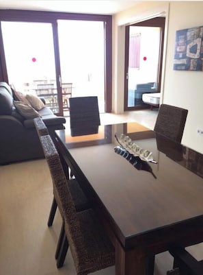 A dining area with a glass-top table, wicker chairs, and a view of the outside.