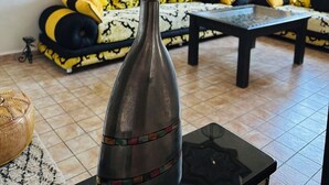 Una sala de estar con un jarrón grande de plumas de pluma dorada, un sofá estampado y una mesa de centro.