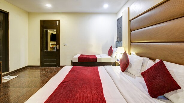 A hotel room with a large bed, a bedside table, a ceiling fan, and a door leading to the bathroom. - Hotel WK Comfort Inn (New Delhi)