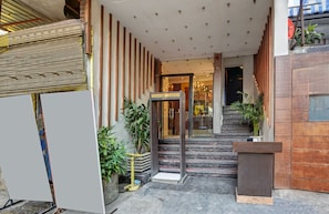 Entrada d'hotel amb una escala, plantes en testos i una recepció.