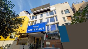 A hotel named 'Hotel White Klove' with a blue sign, a covered entrance, and a visible balcony with plants. - Hotel WK Comfort Inn (New Delhi)