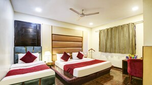 A hotel room with two beds, a ceiling fan, a window with curtains, and a small table with snacks. - Hotel WK Comfort Inn (New Delhi)
