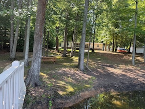 A campsite with a wooden deck, a picnic table, and a small pond. - Skipper's Cove, Lakefront Family Escape w/ Private Dock, Kayaks, Fire Pit & more (Lexington)
