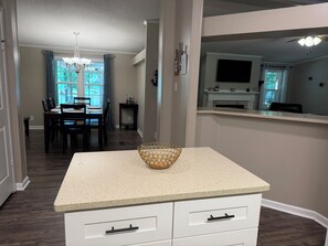 A kitchen with a countertop, a white cabinet, and a dining area with a table and chairs. - Skipper's Cove, Lakefront Family Escape w/ Private Dock, Kayaks, Fire Pit & more (Lexington)