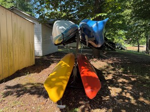 A row of boats parked outdoors, with a building and trees in the background.