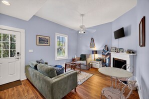 Ein Wohnzimmer mit Sofa, Couchtisch, Kamin, Fernseher und Deckenventilator.
