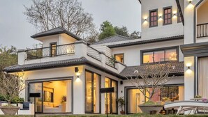 A modern two-story house with large windows, a balcony, and a well-maintained lawn. - Lavender Villa by BasilStays (Calangute)