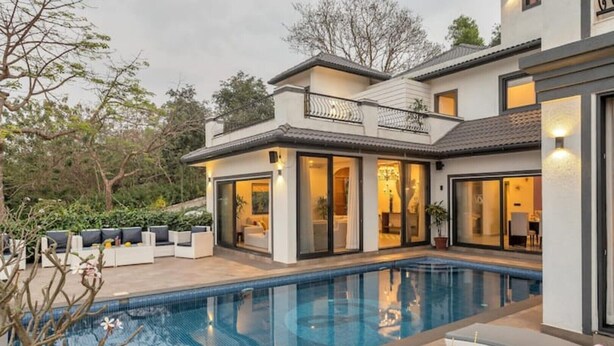 A modern house with a swimming pool, outdoor seating, and large windows. - Lavender Villa by BasilStays (Calangute)