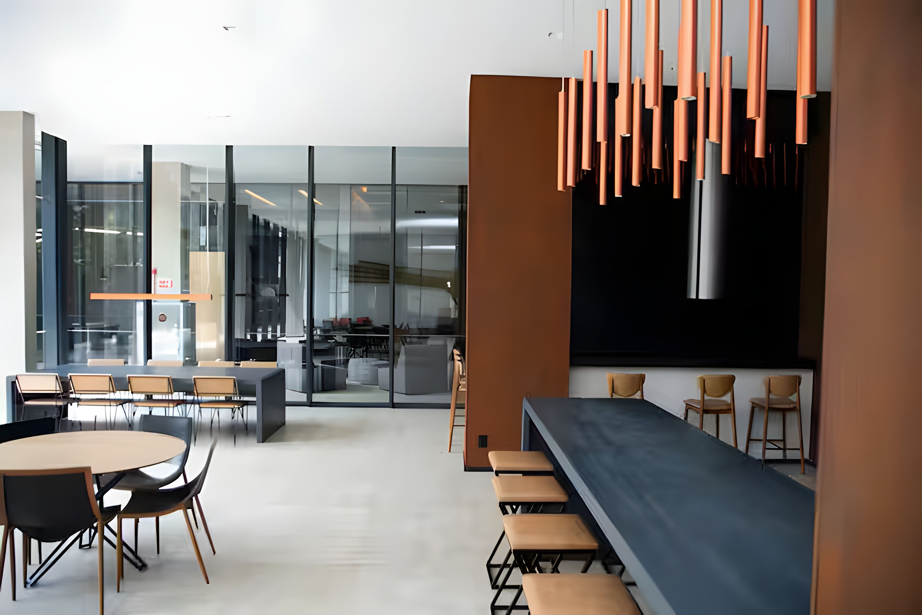 Un espace de bureau moderne comprenant une grande table et des chaises, un coin cuisine et un bar avec des tabourets.