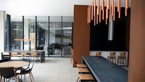 A modern office space with a long table and chairs, a kitchen area, and a bar with stools. - Luxury studio apartment in Vila Olímpia - panoramic view and garage. (São Paulo)
