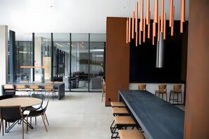 A modern office space with a long table and chairs, a kitchen area, and a bar with stools. - Luxury studio apartment in Vila Olímpia - panoramic view and garage. (São Paulo)
