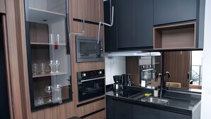 A modern kitchen with built-in appliances, a black countertop, and wooden cabinetry. - Luxury studio apartment in Vila Olímpia - panoramic view and garage. (São Paulo)