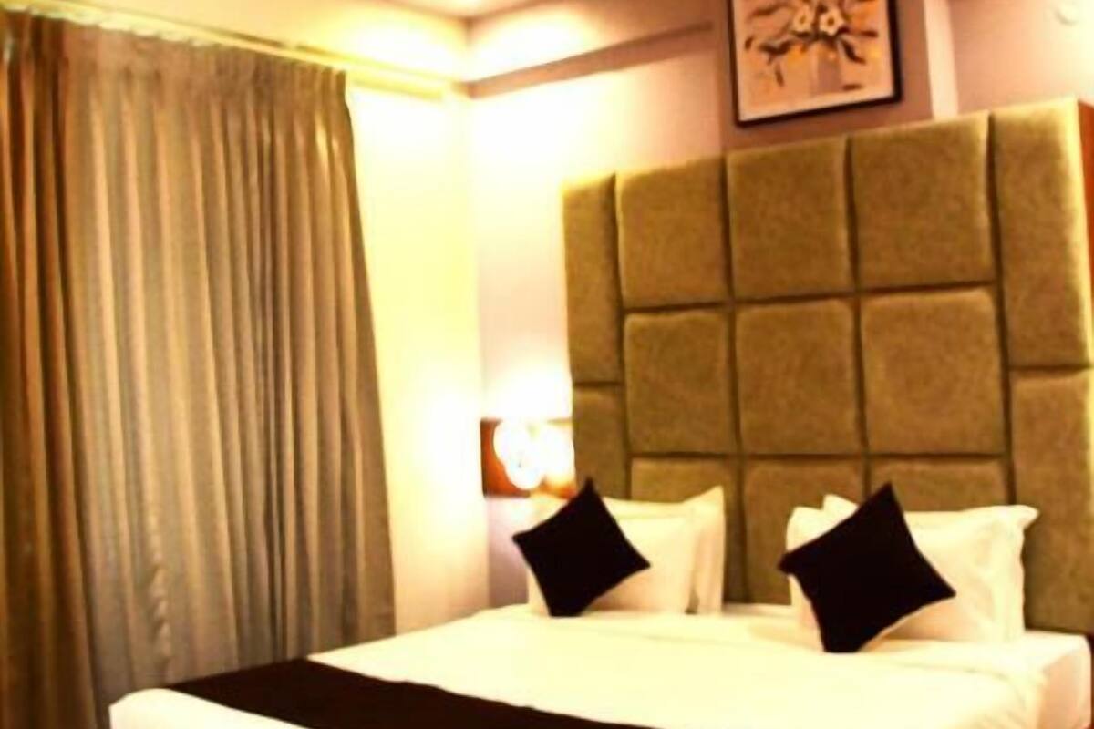Una habitación de hotel con cama, ventilador de techo, cabecera y un cuadro en la pared.