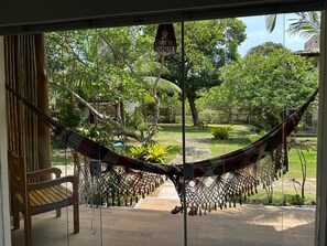 A hammock in a room with a view of a garden. - Modern Ground Floor Beachfront Studio: Smart Economy (Maraú)