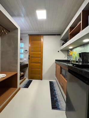 A kitchen with a wooden door, a countertop, and a sink. - Modern Ground Floor Beachfront Studio: Smart Economy (Maraú)