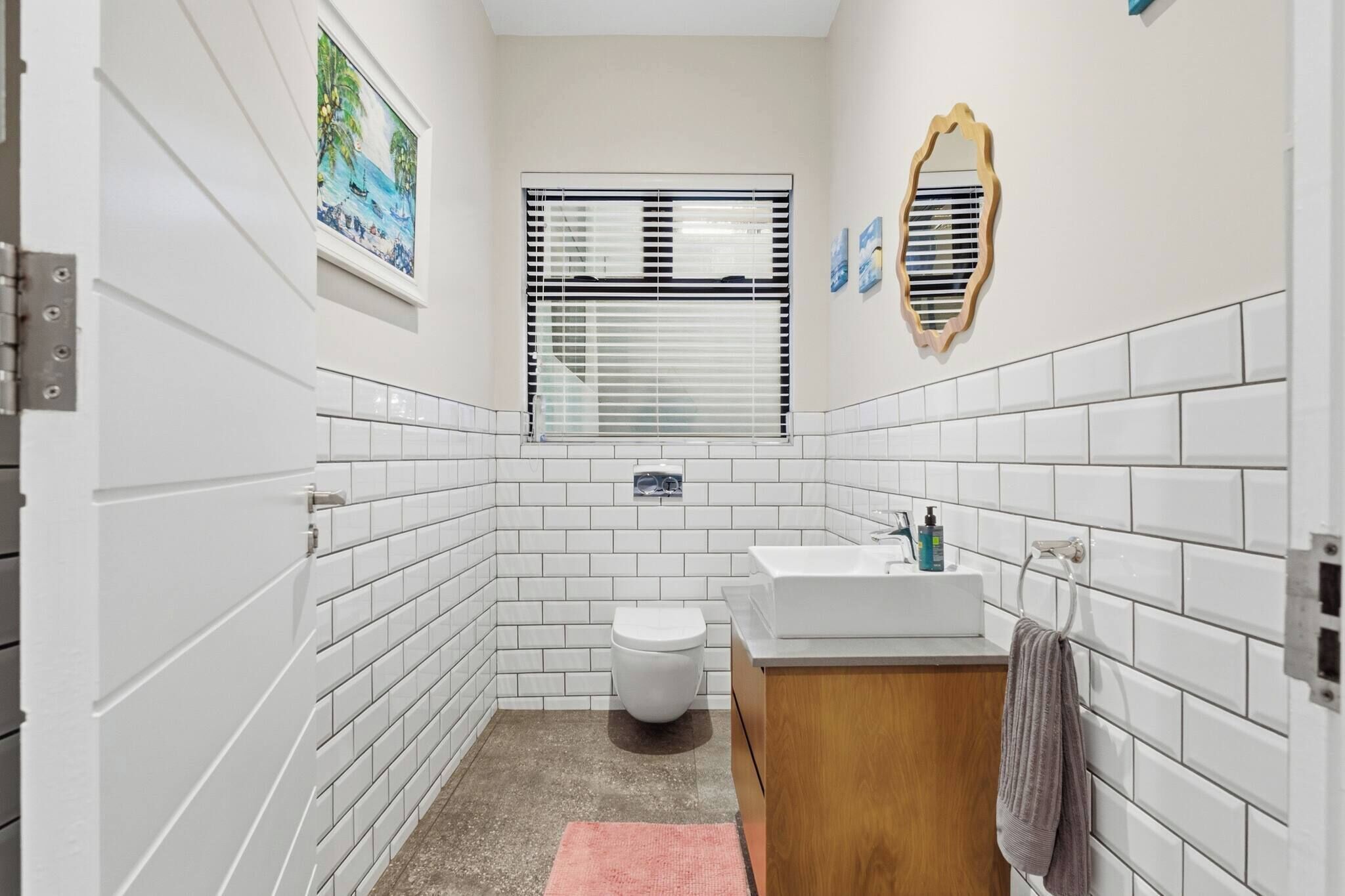 A small bathroom with white tiled walls, a toilet, a sink, and a mirror.
