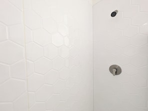 A shower with a hexagonal tile pattern and a metallic showerhead.