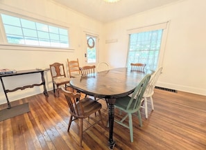 Une salle à manger avec une table ronde, des chaises en bois et une petite table d’appoint.