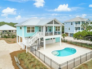 Ein zweistöckiges Haus mit Pool, überdachter Terrasse und umzäunter Garten.