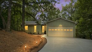 Ein Haus mit Garage, Auffahrt und einem angelegten Garten mit Beleuchtung.