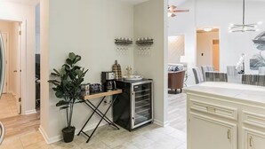 Eine moderne Küche mit einer Kaffeestation, einem Essbereich mit gestreiften Stühlen und einem großen Schrank.